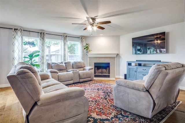 living room featuring a fireplace, light hardwood / wood-style floors, and ceiling fan