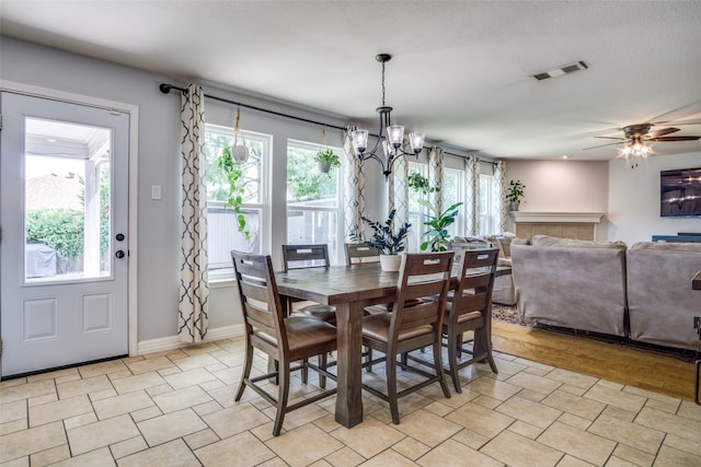 dining area with light hardwood / wood-style floors, a textured ceiling, plenty of natural light, and ceiling fan with notable chandelier