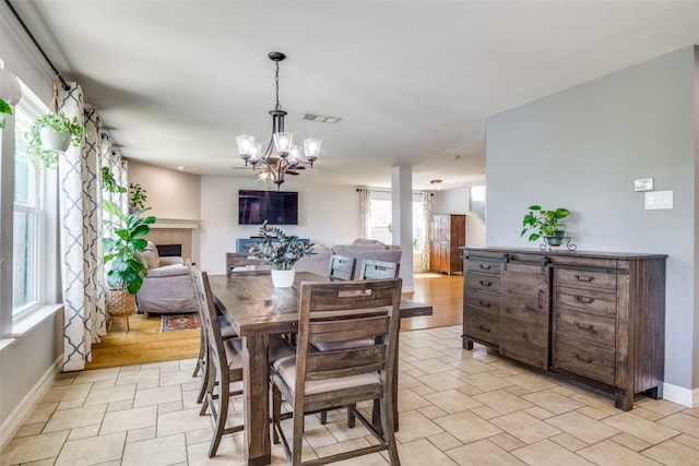 dining area with a tile fireplace, light hardwood / wood-style floors, and an inviting chandelier