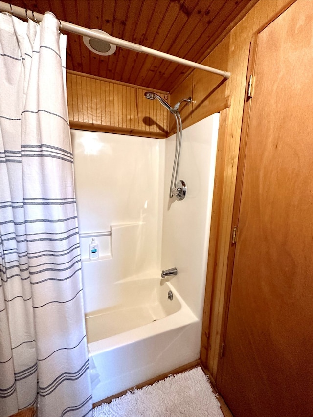 bathroom with wood ceiling, wooden walls, and shower / tub combo with curtain