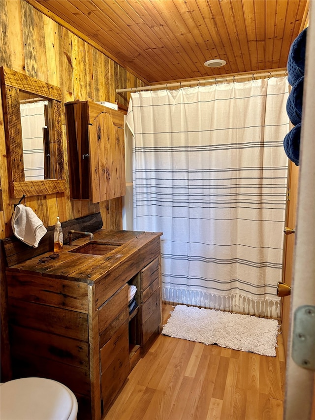 bathroom with wooden ceiling, hardwood / wood-style floors, toilet, and wood walls