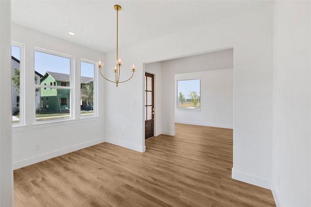 unfurnished dining area with a chandelier and hardwood / wood-style floors