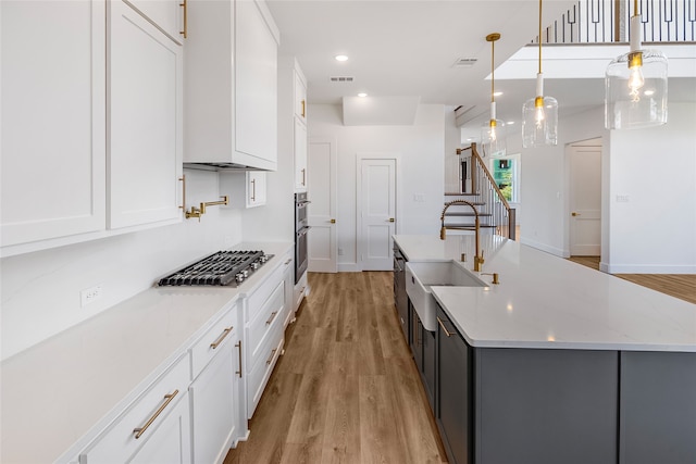 kitchen featuring light hardwood / wood-style floors, white cabinetry, light stone countertops, and hanging light fixtures