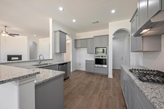 kitchen featuring dark wood-type flooring, sink, range hood, gray cabinetry, and stainless steel appliances