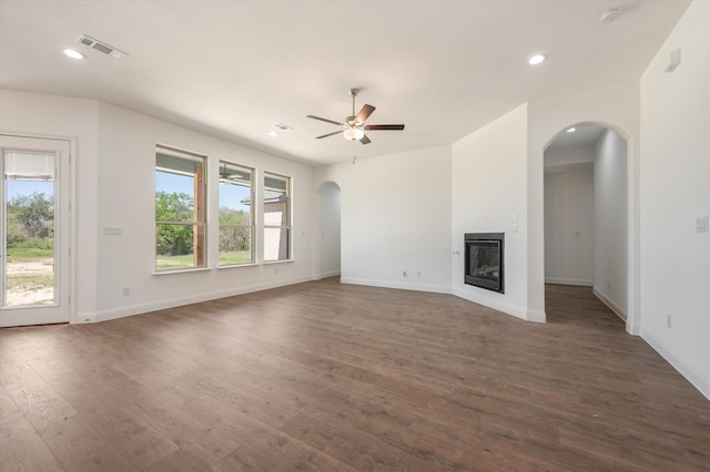 unfurnished living room with dark wood-type flooring, ceiling fan, and plenty of natural light