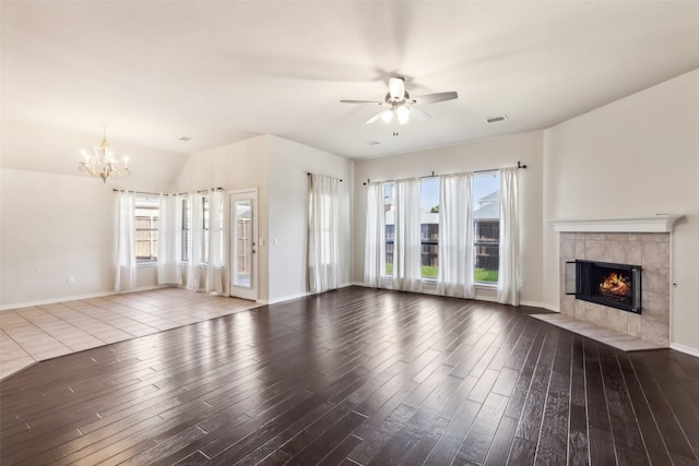 unfurnished living room with ceiling fan with notable chandelier, lofted ceiling, a fireplace, and hardwood / wood-style floors