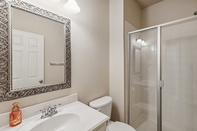 bathroom featuring a shower with door, toilet, and vanity