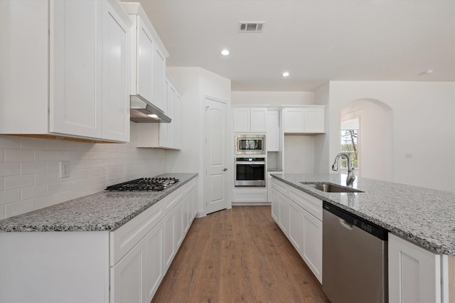 kitchen with sink, light stone countertops, white cabinets, appliances with stainless steel finishes, and light hardwood / wood-style floors