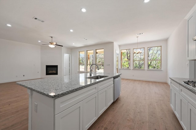 kitchen featuring appliances with stainless steel finishes, white cabinetry, sink, and light hardwood / wood-style floors