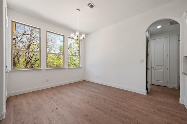 spare room with hardwood / wood-style flooring and an inviting chandelier