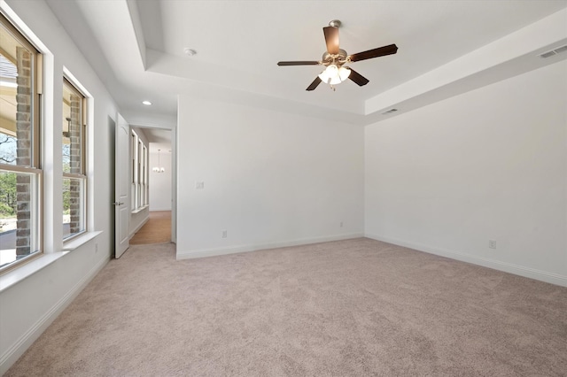 spare room with light carpet, a tray ceiling, and ceiling fan