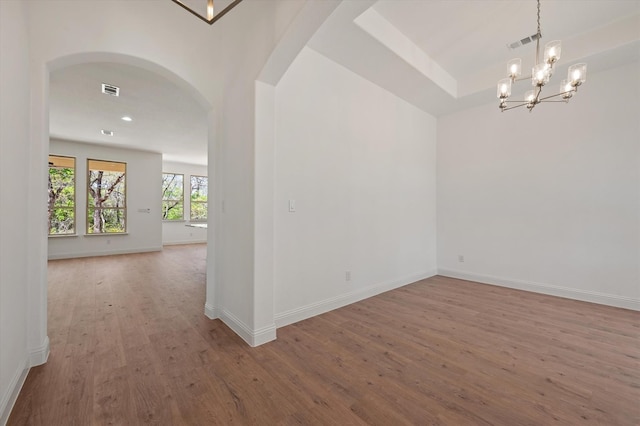 empty room featuring a chandelier and hardwood / wood-style flooring