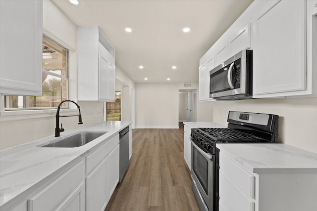 kitchen with appliances with stainless steel finishes, white cabinets, and sink