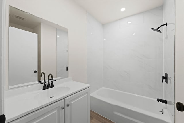 bathroom featuring vanity, tiled shower / bath combo, and wood-type flooring