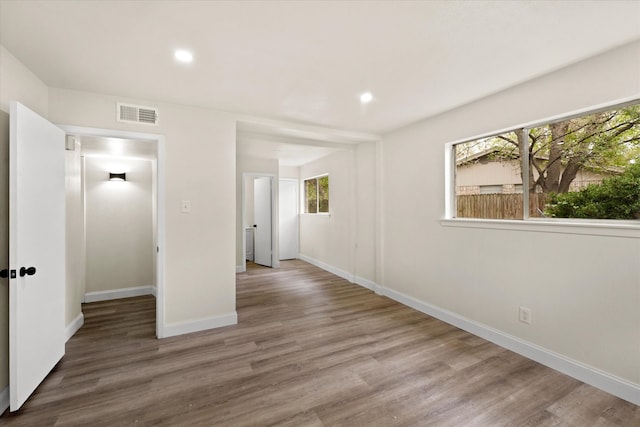 unfurnished bedroom featuring hardwood / wood-style floors and multiple windows