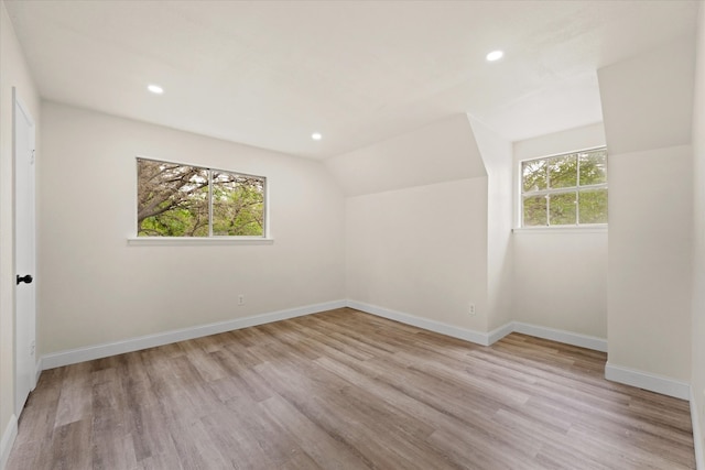 additional living space with vaulted ceiling and light wood-type flooring