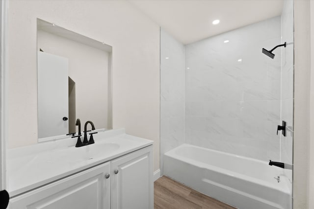 bathroom with vanity, hardwood / wood-style flooring, and tiled shower / bath