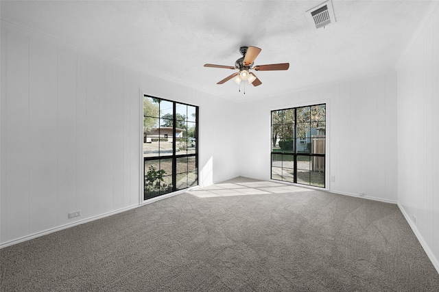 carpeted spare room featuring plenty of natural light, ornamental molding, and ceiling fan