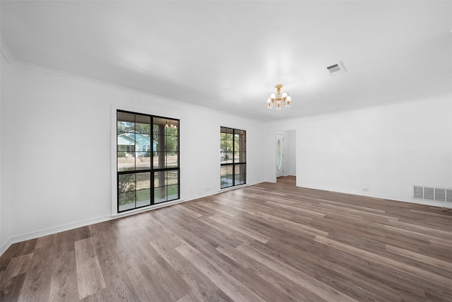 spare room featuring ornamental molding, hardwood / wood-style flooring, and a notable chandelier