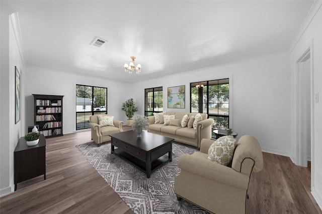 living room featuring dark hardwood / wood-style floors, ornamental molding, and an inviting chandelier