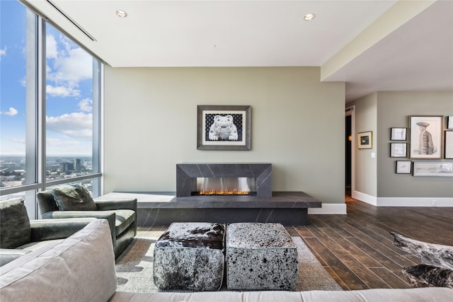 living room with dark wood-type flooring, a high end fireplace, and a wall of windows