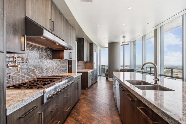 kitchen featuring stainless steel gas stovetop, sink, dark hardwood / wood-style flooring, decorative backsplash, and light stone countertops