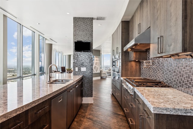 kitchen featuring sink, light stone counters, appliances with stainless steel finishes, a kitchen island with sink, and decorative backsplash