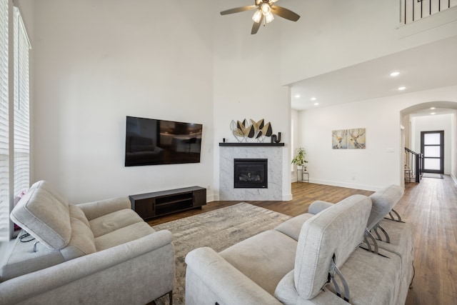 living room featuring wood-type flooring, a high ceiling, and ceiling fan