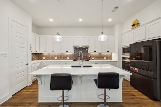 kitchen with white cabinets, a kitchen island with sink, and dark hardwood / wood-style flooring