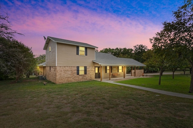 back house at dusk with central AC, a yard, and a patio area