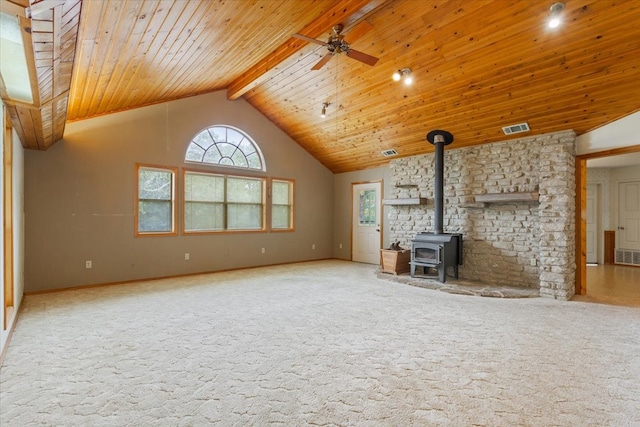 unfurnished living room with wood ceiling, beamed ceiling, a wood stove, carpet floors, and ceiling fan