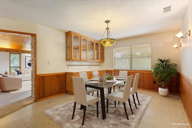 dining space with wooden walls and a textured ceiling