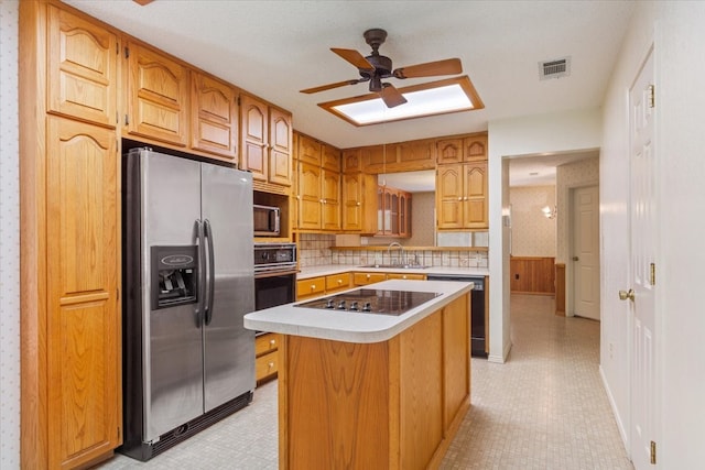 kitchen featuring black appliances, sink, a kitchen island, backsplash, and ceiling fan