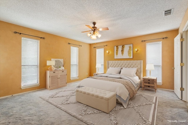 bedroom featuring carpet flooring, multiple windows, a textured ceiling, and ceiling fan