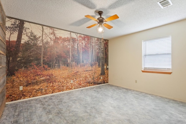 empty room featuring a textured ceiling, carpet floors, and ceiling fan