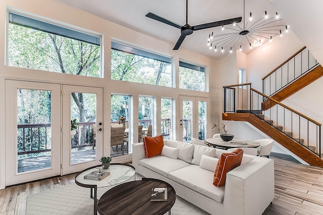 living room with french doors, a towering ceiling, and ceiling fan with notable chandelier