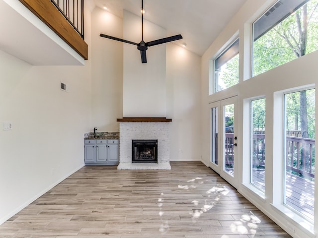 unfurnished living room featuring a fireplace, a high ceiling, plenty of natural light, and ceiling fan