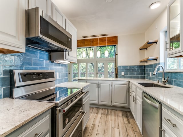 kitchen with light stone countertops, sink, white cabinetry, and stainless steel appliances