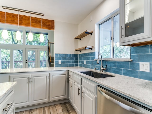 kitchen featuring white cabinetry, dishwasher, sink, light stone counters, and light hardwood / wood-style floors