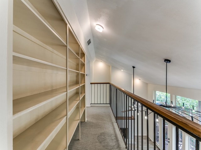 hallway with carpet floors and vaulted ceiling