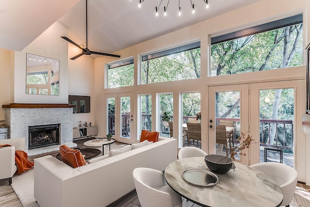 living room with a healthy amount of sunlight, a fireplace, high vaulted ceiling, and french doors