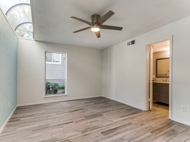 empty room with ceiling fan, light wood-type flooring, sink, and a wealth of natural light