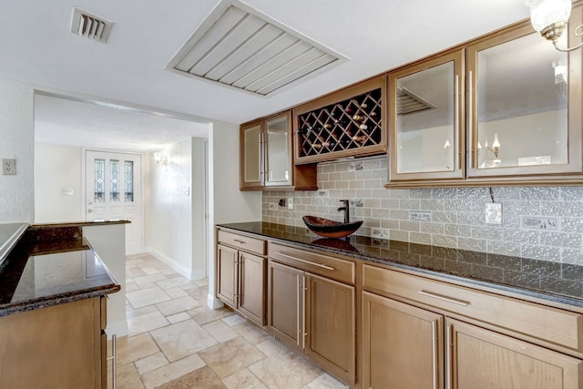 kitchen featuring decorative backsplash and dark stone countertops