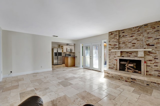 unfurnished living room with french doors and a large fireplace