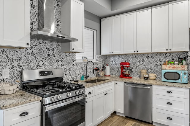 kitchen featuring sink, white cabinets, wall chimney range hood, and stainless steel appliances