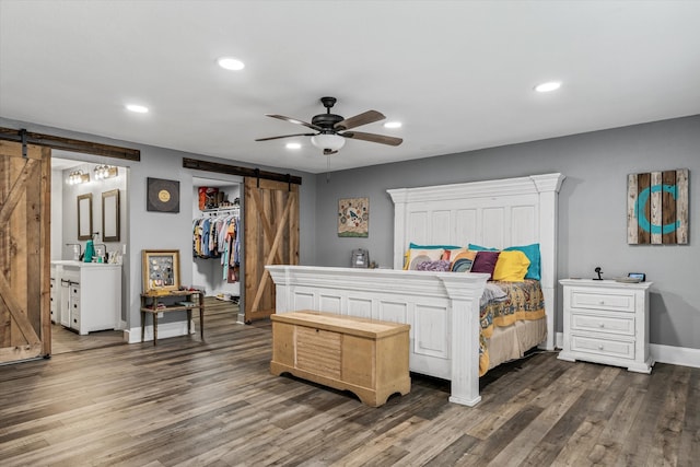 bedroom with a closet, a barn door, ceiling fan, and dark hardwood / wood-style flooring