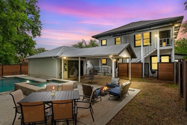 back house at dusk with a fenced in pool and a patio