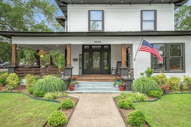 view of exterior entry with a yard and a porch