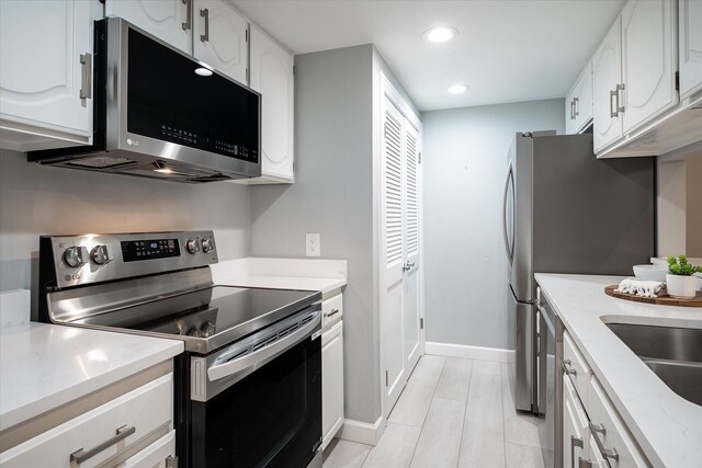 kitchen with white appliances, light hardwood / wood-style flooring, sink, and white cabinets