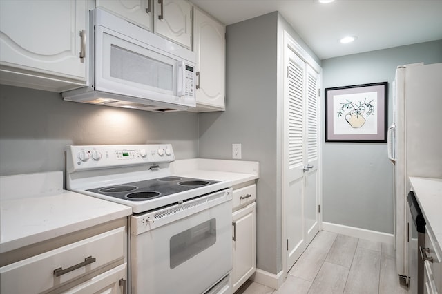 kitchen with white cabinetry, white appliances, and light hardwood / wood-style floors